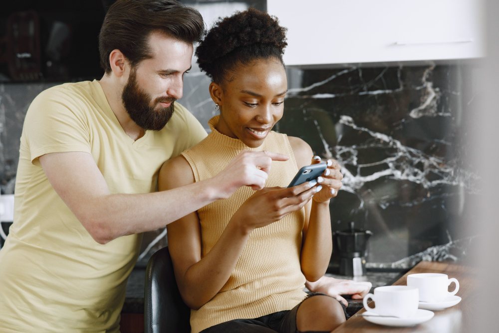 Ein Paar sitzt zusammen und lächelt auf ein Handy