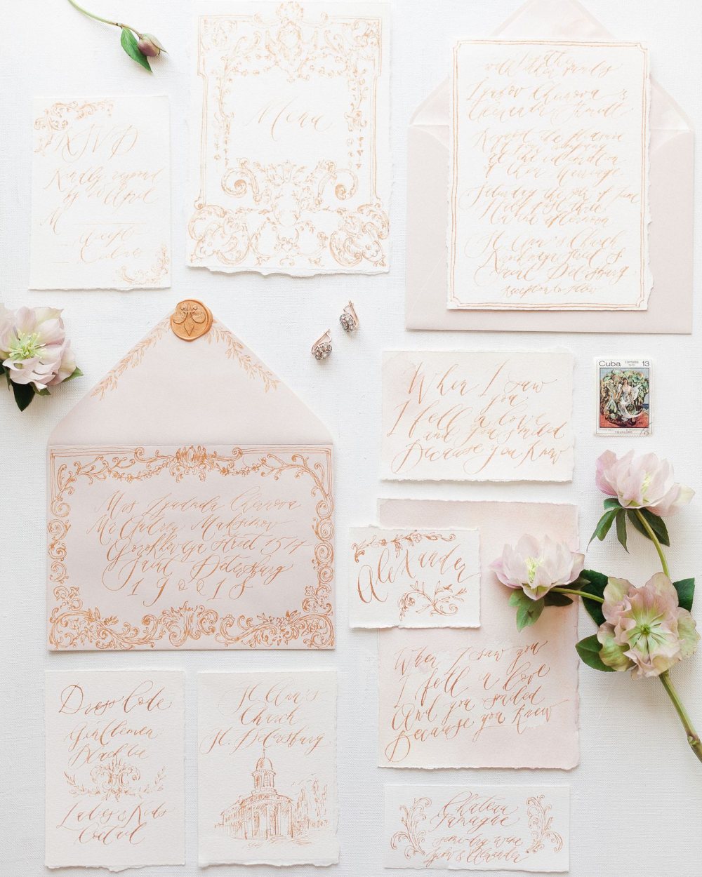 Ein zart rosa-goldenes Hochzeitseinladungsset mit Kalligrafie, drapiert mit Blumen und einem Wachssiegel