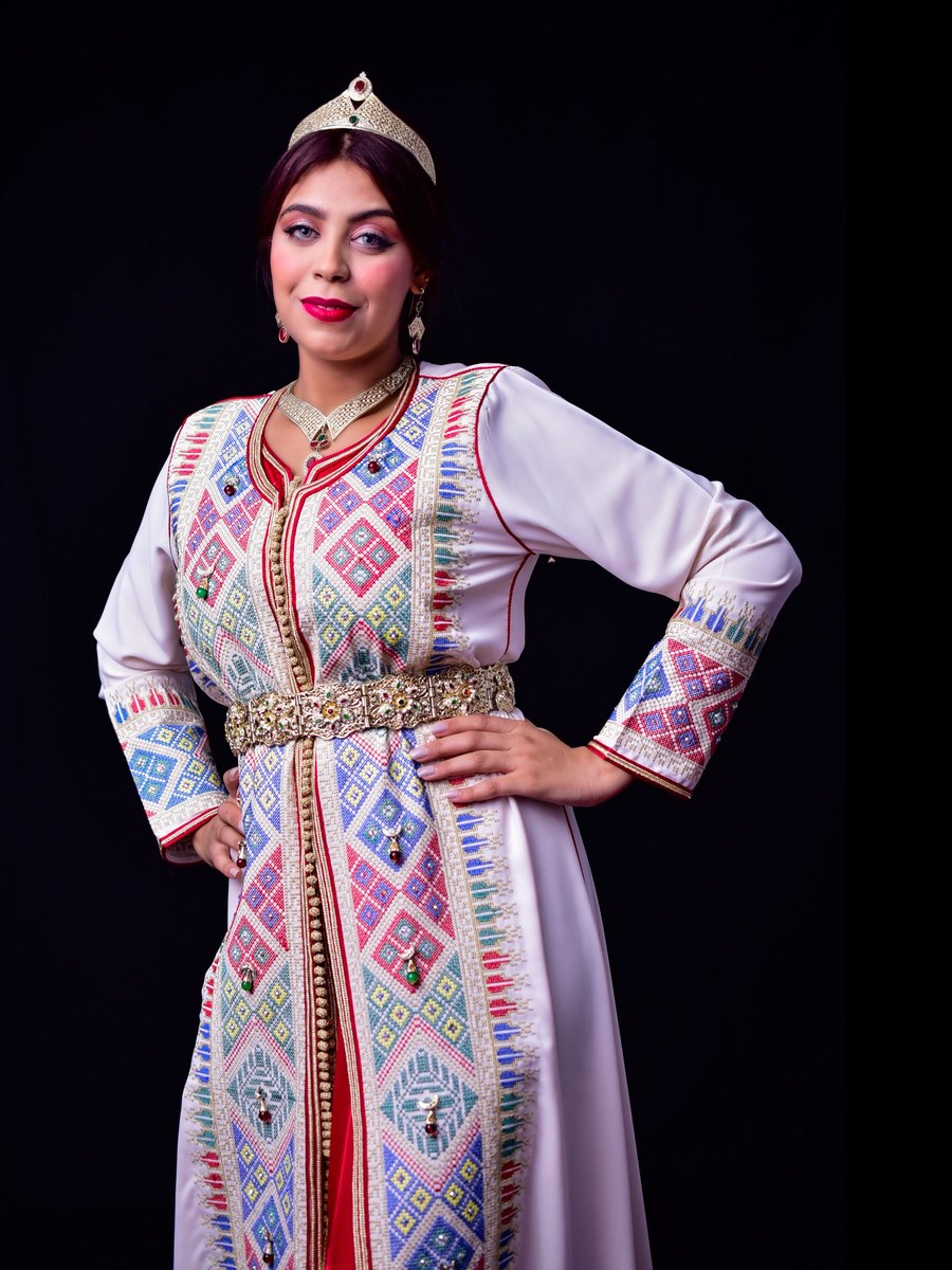 A woman in an elaborate traditional caftan with embroidered detail and a crown-like headpiece
