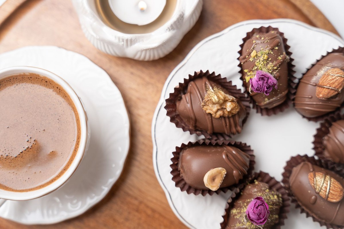 Arabic coffee and a plate of chocolate-covered dates with rose petals and gold leaf